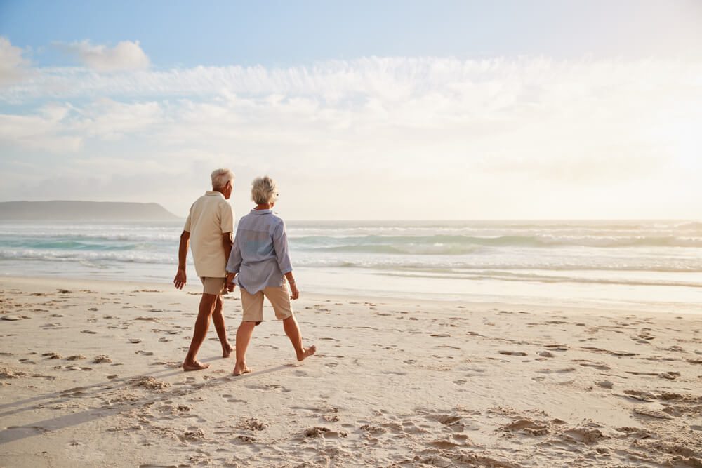 A couple walking along the beach, which is one of the top results when searching for what to do in Naples on a snowbird vacation.